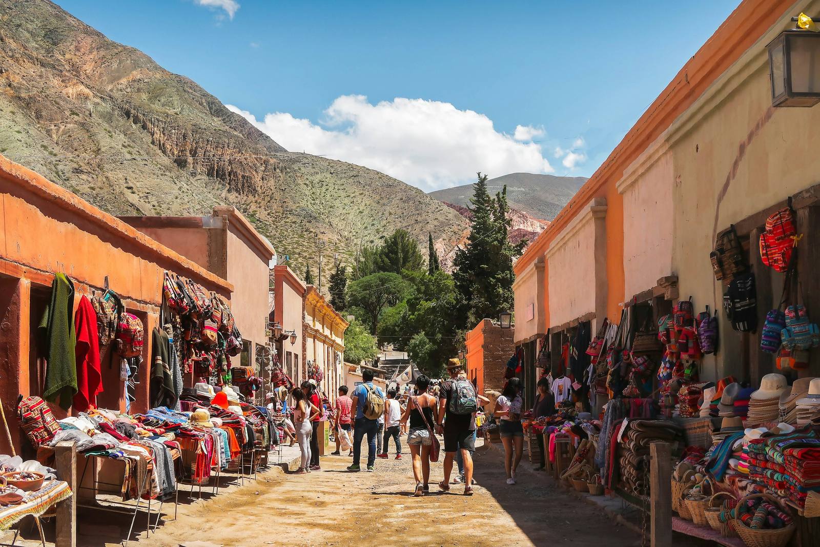 Calle de tierra de Purmamarca, Jujuy, con casas de adobe, puestos de tejidos y el cerro detrás.