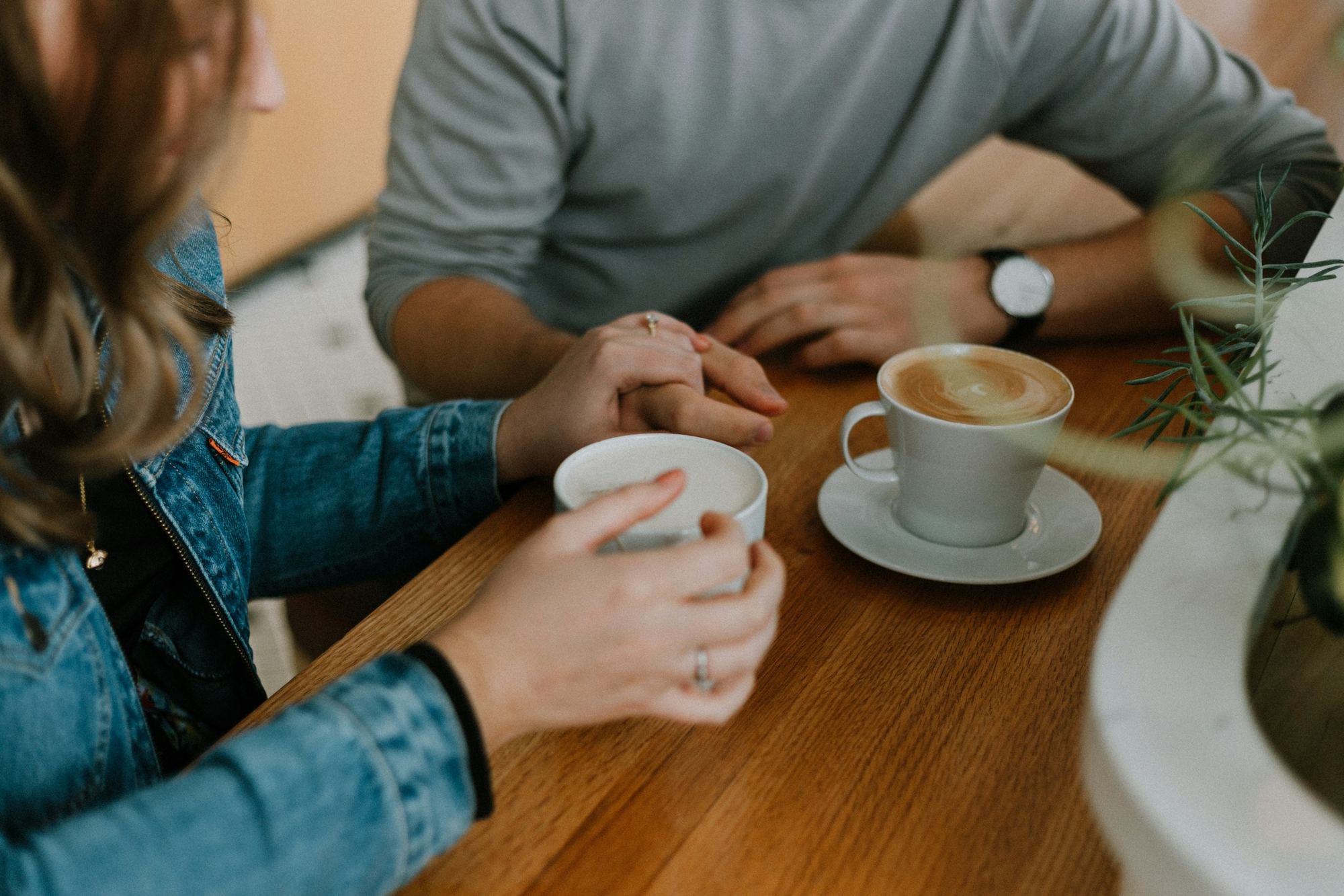 Dos personas conversando con café sobre una mesa de madera.